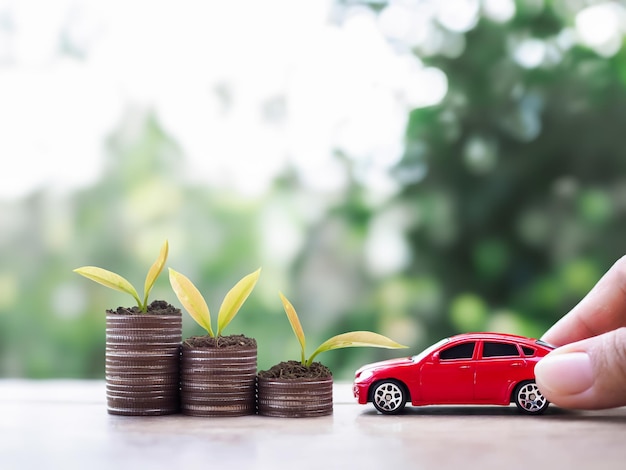 La voiture de jouet et les plantes qui poussent sur une pile de pièces Le concept de croissance d'entreprise économiser de l'argent et gérer le succès de l'entreprise de transport