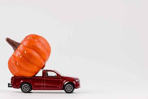 Voiture jouet vintage rouge avec de petites citrouilles d'Halloween sur le toit