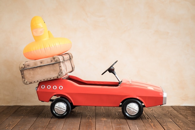Photo voiture jouet vintage avec valise vacances d'été et concept de voyage
