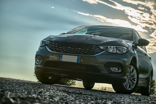 Voiture moderne prise d'en bas avec grand angle derrière avec coucher de soleil et une belle lumière qui contraste.