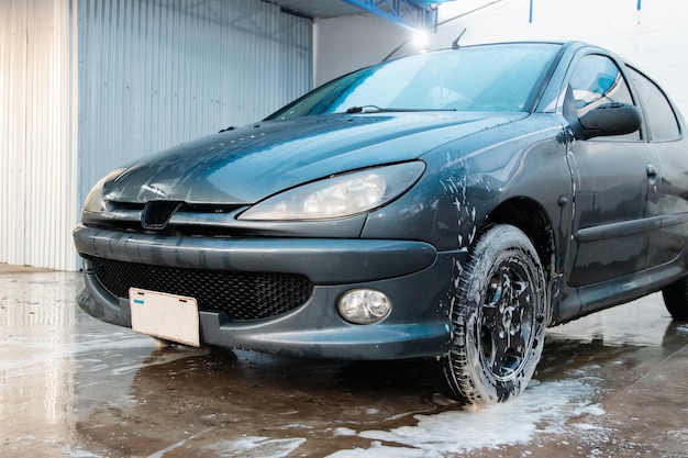 Voiture avec de la mousse sur les roues dans le lave-auto