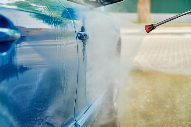 Voiture de nettoyage avec de l'eau à haute pression à la station de lavage de voiture