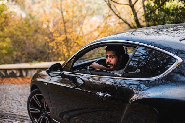 Voiture noire dans le jardin d'été, chauffeur aux commandes