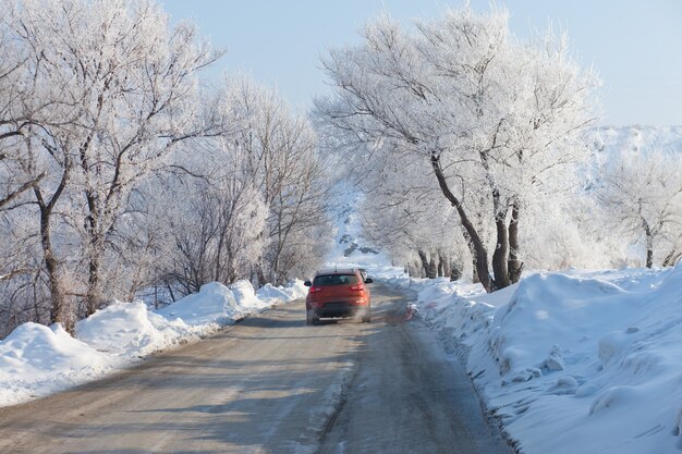 Voiture orange se déplaçant sur la belle route d'hiver