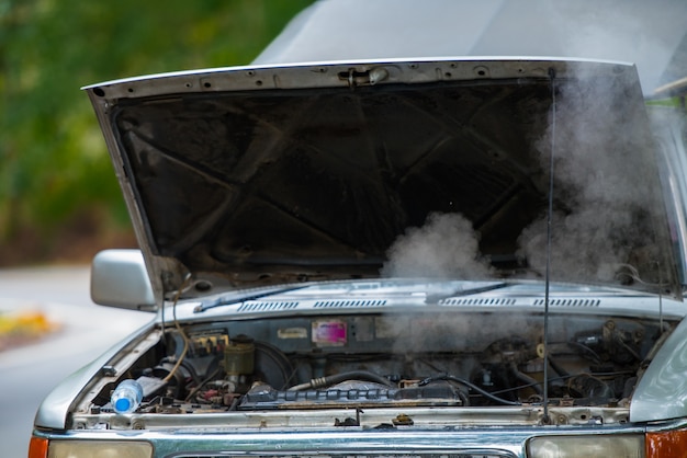 Voiture en panne avec moteur qui fume, moteur surchauffé sur la route.