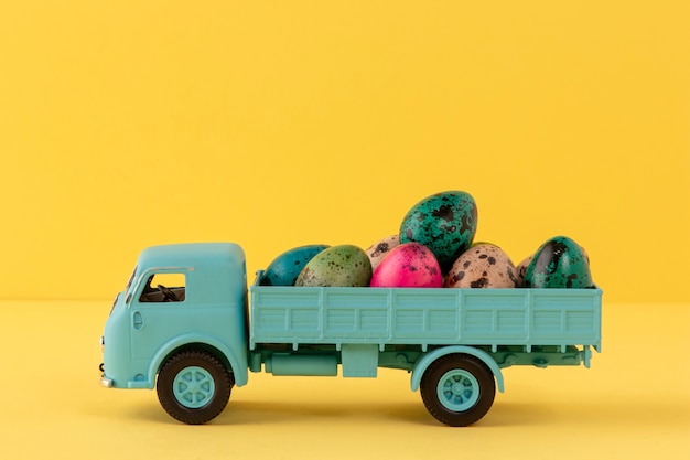 Voiture de Pâques bleue avec oeufs et fond jaune