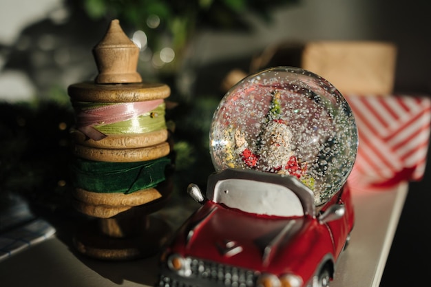 Une voiture de Père Noël rétro avec des cadeaux de Noël, un globe de neige avec le Père Noël.