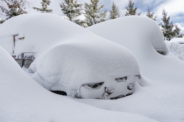 Voiture recouverte de neige après une forte tempête de neigeLes véhicules sont recouverts de neige lors d'une forte chute de neige