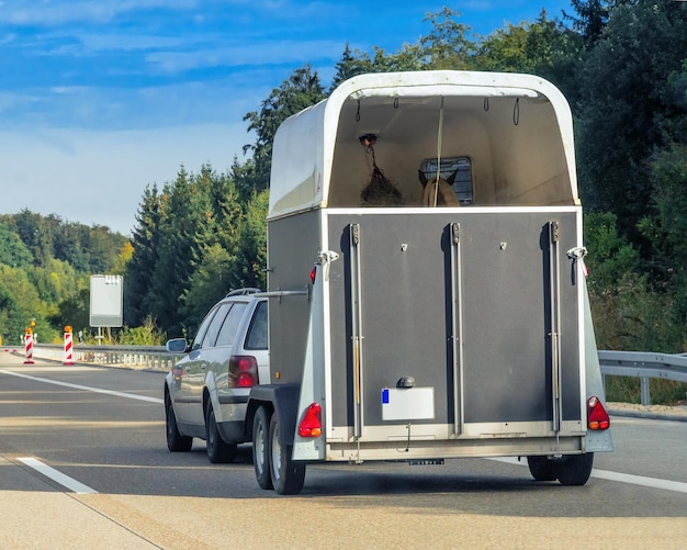 Voiture avec remorque à cheval sur la route en Suisse.