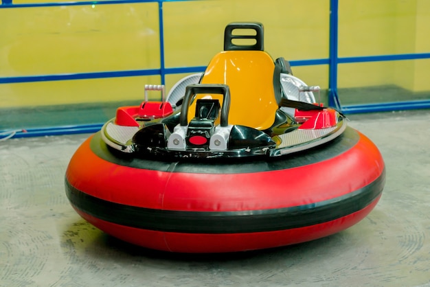 Une voiture rouge arrondie avec une chaise jaune se dresse au parc d'attractions intérieur. Conduire. Chauffeur. Amusement. Attraction