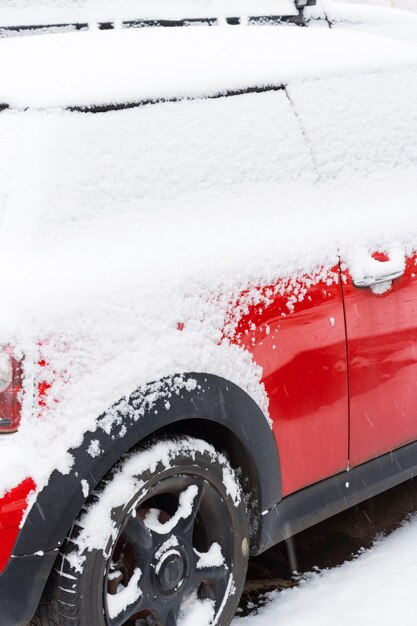 Voiture rouge couverte de neige sur le stationnement en hiver