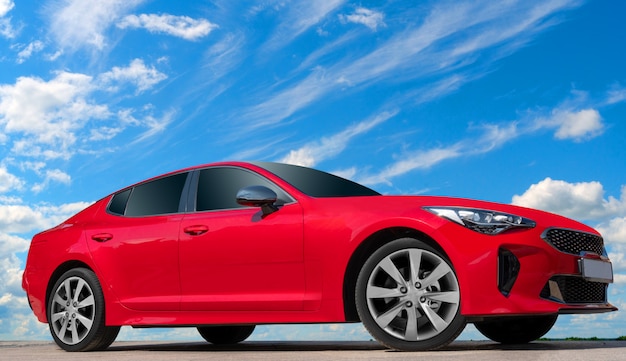 Voiture rouge sur fond de ciel bleu avec des nuages blancs.