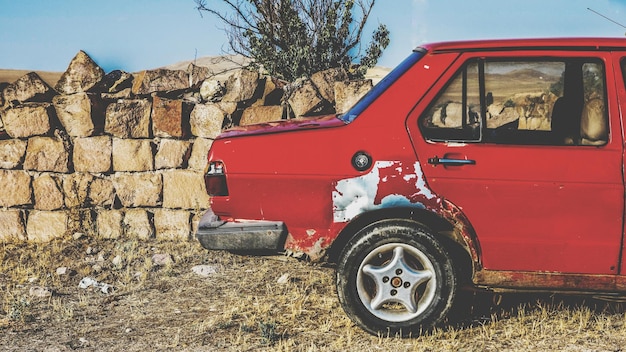 Photo voiture rouge par le mur de pierre