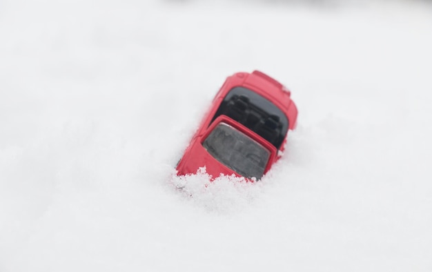 Voiture rouge sous la neige dans une congère après une tempête de neige d'ouragan