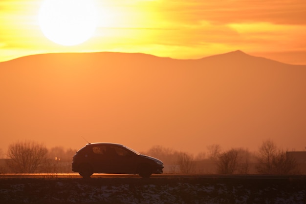 Voiture roulant rapidement sur une route interurbaine au coucher du soleil Circulation routière en soirée