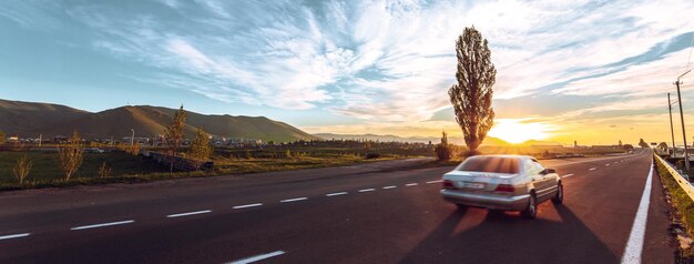 La voiture roule sur l'autoroute au coucher du soleil