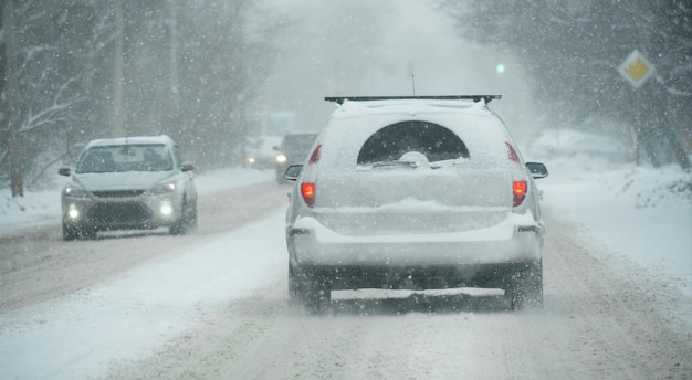 Photo la voiture roule sur une ville d'hiver dans un blizzard