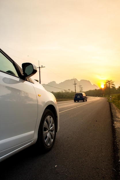 Photo la voiture sur la route au coucher du soleil