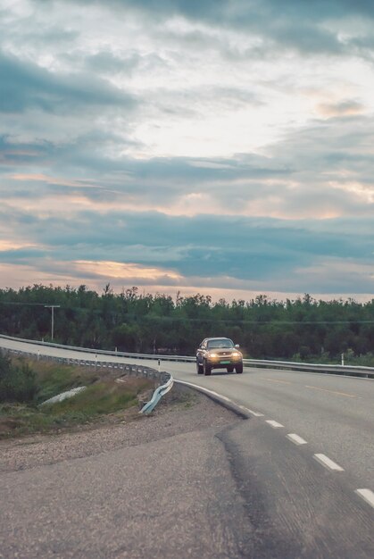 Voiture sur la route contre un ciel nuageux du soir