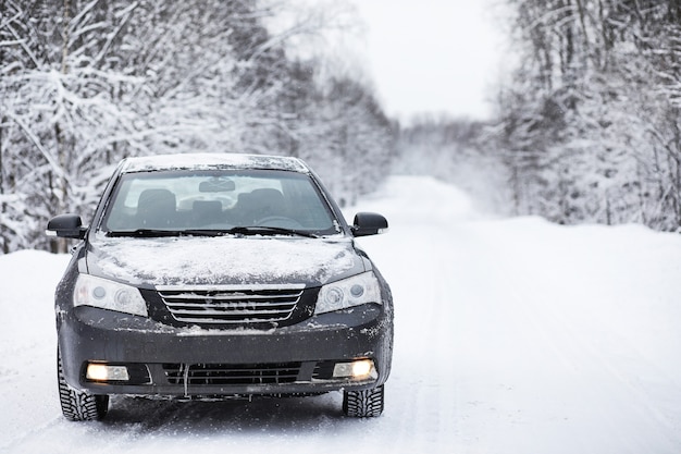 La voiture se dresse sur une route enneigée par temps nuageux en hiver