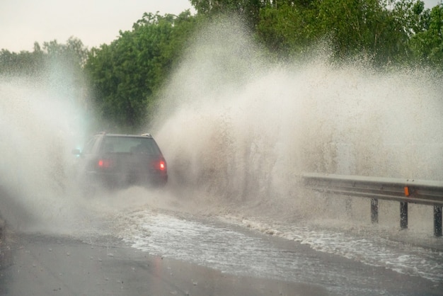 La voiture se heurte à une grande flaque d'eau à de fortes pluies, de l'eau éclaboussant la voiture.