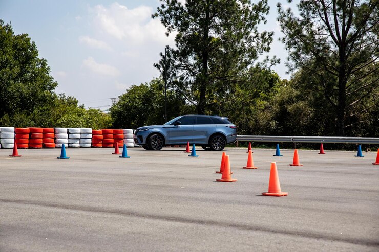 Une voiture de sport se tient sur le parking avec des cônes en arrière-plan