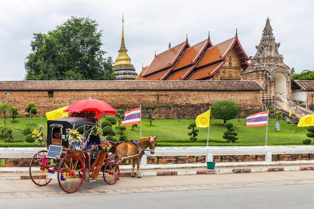 Photo une voiture tirée par des chevaux, le symbole de la province, est devant wat phra that lampang luang dans la province de lampang en thaïlande