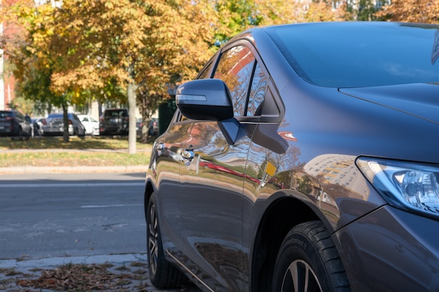 Voiture de tourisme garée sur la chaussée d'une route de ville par une chaude journée ensoleillée d'automne