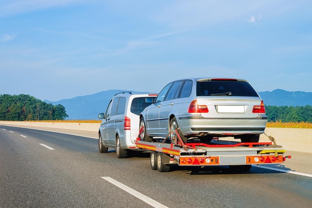 Voiture transportant une remorque avec un nouveau véhicule sur la route goudronnée en Slovénie.