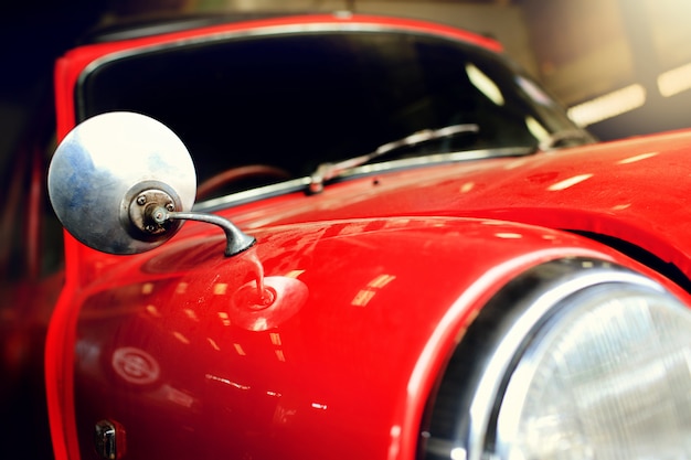 Une voiture vintage rouge avec de la poussière dans le garage.