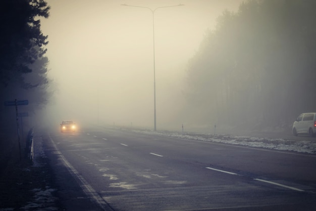 Voitures dans le brouillard Mauvais temps hivernal et trafic automobile dangereux sur la route Véhicules légers dans le brouillard