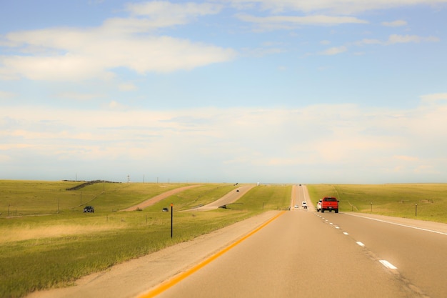 Des voitures sur la route par des champs contre le ciel