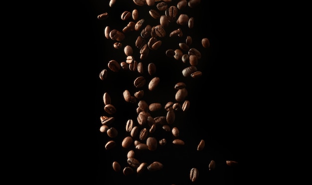 Vol de grains de café torréfiés sur fond noir