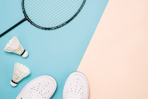 Photo volant et raquette de badminton avec des chaussures de sport sur fond de couleur pastel