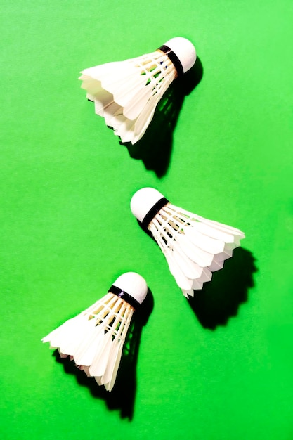 Volants de cocept d'activité d'été pour le jeu de badminton sur fond vert bruyant avec lumière dure et ombres