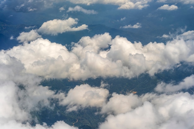 Voler au-dessus de la terre et au-dessus des nuages sur le territoire de Kota Kinabalu, île de Bornéo, Malaisie. Vue de la fenêtre de l'avion. L'avion vole dans le ciel au-dessus de la terre.