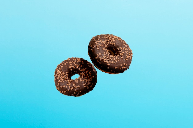 Voler dans l'air Donuts avec du glaçage au chocolat sur un bleu. Boulangerie, concept de cuisson.