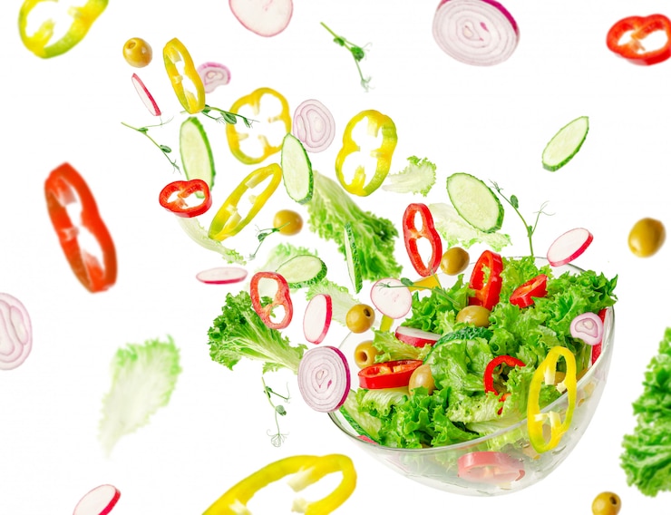 Photo voler les ingrédients de la salade de légumes sur un bol transparent. vitamines et concept de saine alimentation.