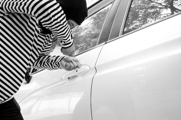 Photo un voleur casse la serrure de la voiture.