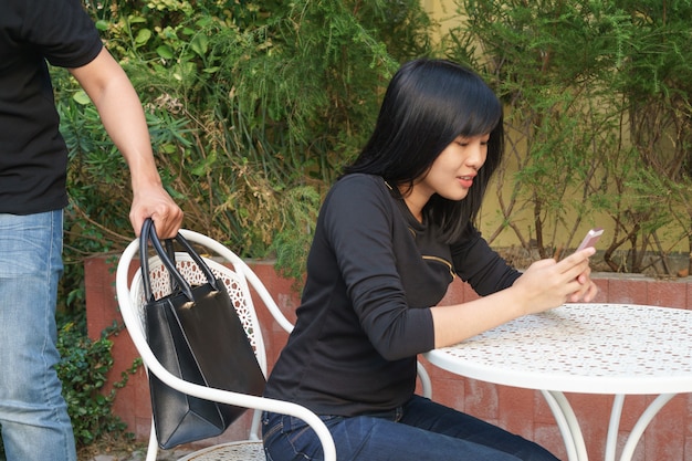 Photo voleur essayant de voler et de s'éloigner du sac à bandoulière pendant que la femme utilise un téléphone portable