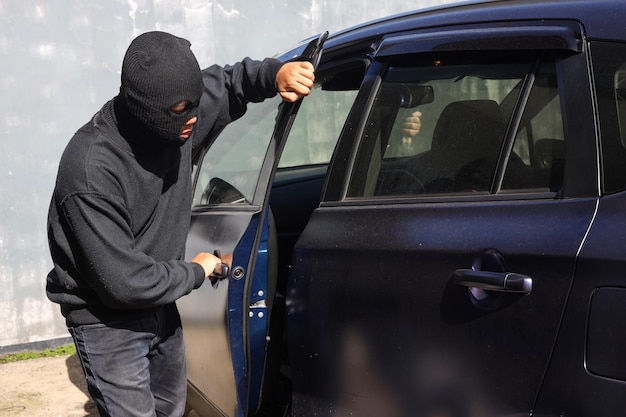 Un voleur qui vole une voiture automobile essaie d'ouvrir la porte