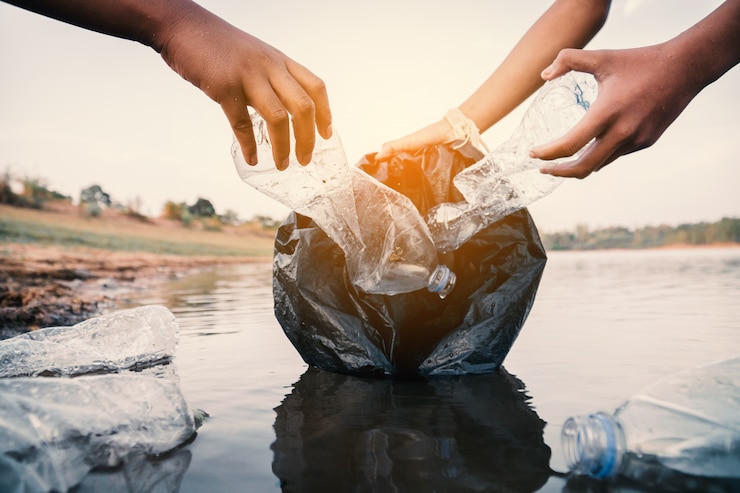 Photo le volontaire qui ramasse une bouteille de plastique dans la rivière protège l’environnement contre la pollution.