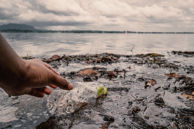 Le volontaire ramassant une bouteille de plastique dans la rivière