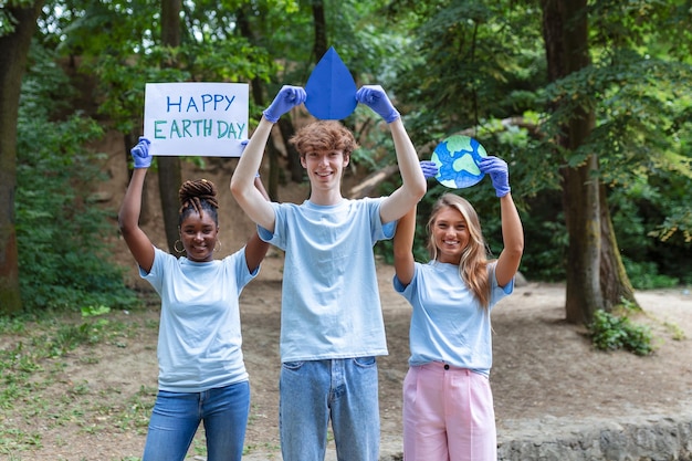 Des volontaires heureux tenant une pancarte avec le message "Joyeux jour de la Terre" Bénévolat caritatif nettoyant les gens et le concept d'écologie