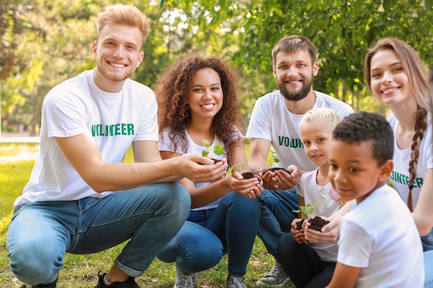 Photo volontaires avec de jeunes plantes à l'extérieur