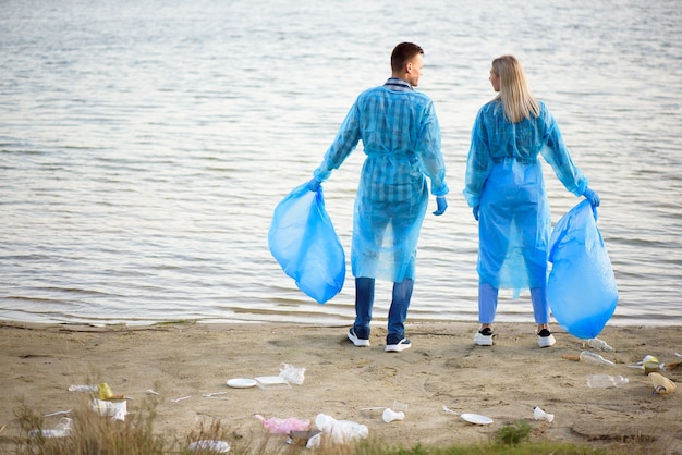 Volontaires ramassant des bouteilles en plastique dans un sac poubelle, écologie, nature, pollution, ordures, soins, volontariat caritatif, environnement communautaire.