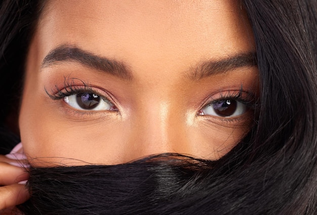 Vos cheveux sont votre bouclier Portrait en gros plan d'une jolie jeune femme posant avec ses cheveux sur son visage en studio