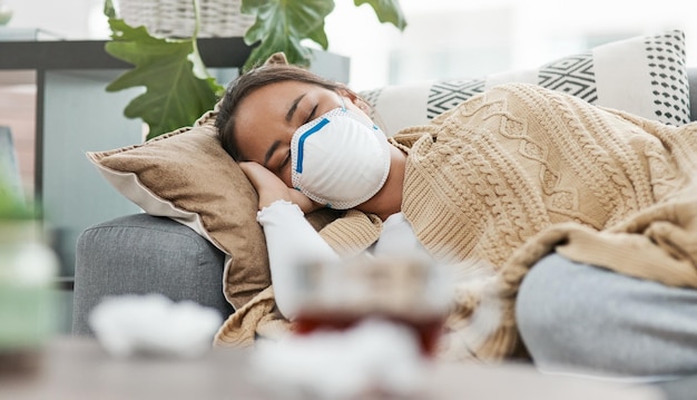 Votre corps a besoin de tout le repos qu'il peut obtenir Photo d'une femme portant un masque allongée malade à la maison