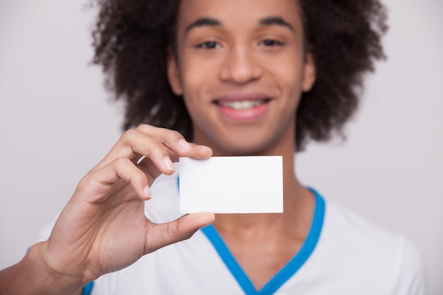 Photo votre texte ici. joyeux adolescent africain tenant une carte en plastique et souriant à la caméra