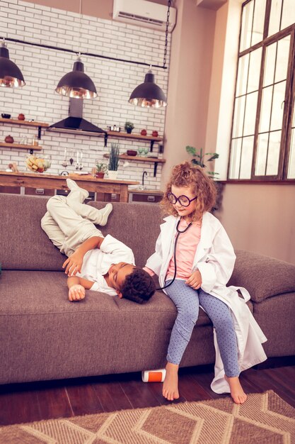 Vouloir dormir. Jolie fille inclinant la tête en jouant avec un stéthoscope